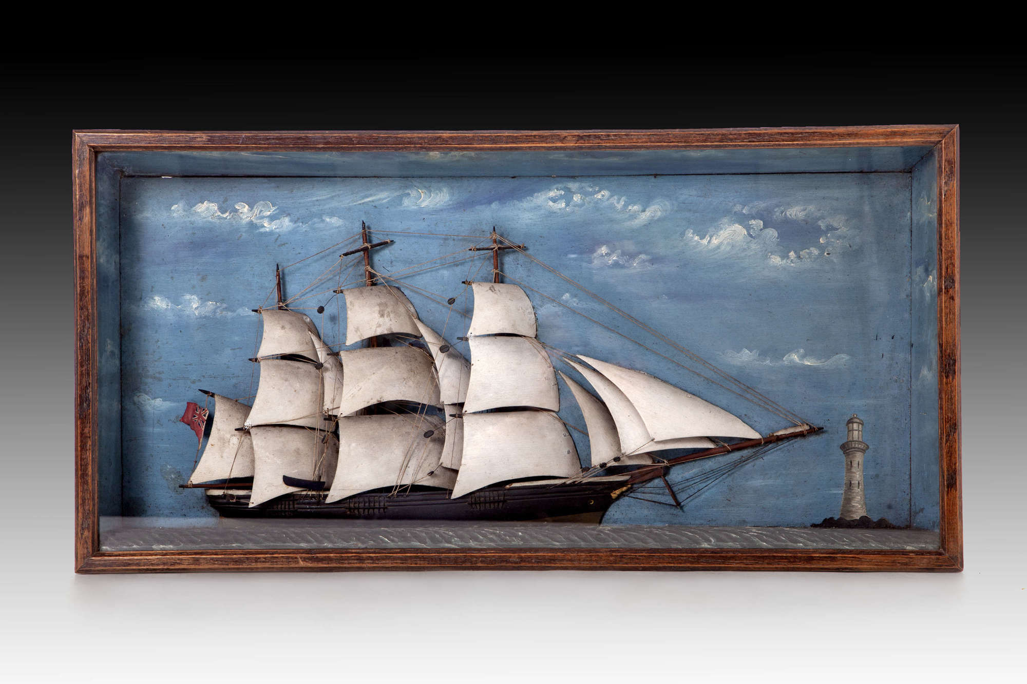 A diorama of a clipper off shore with lighthouse