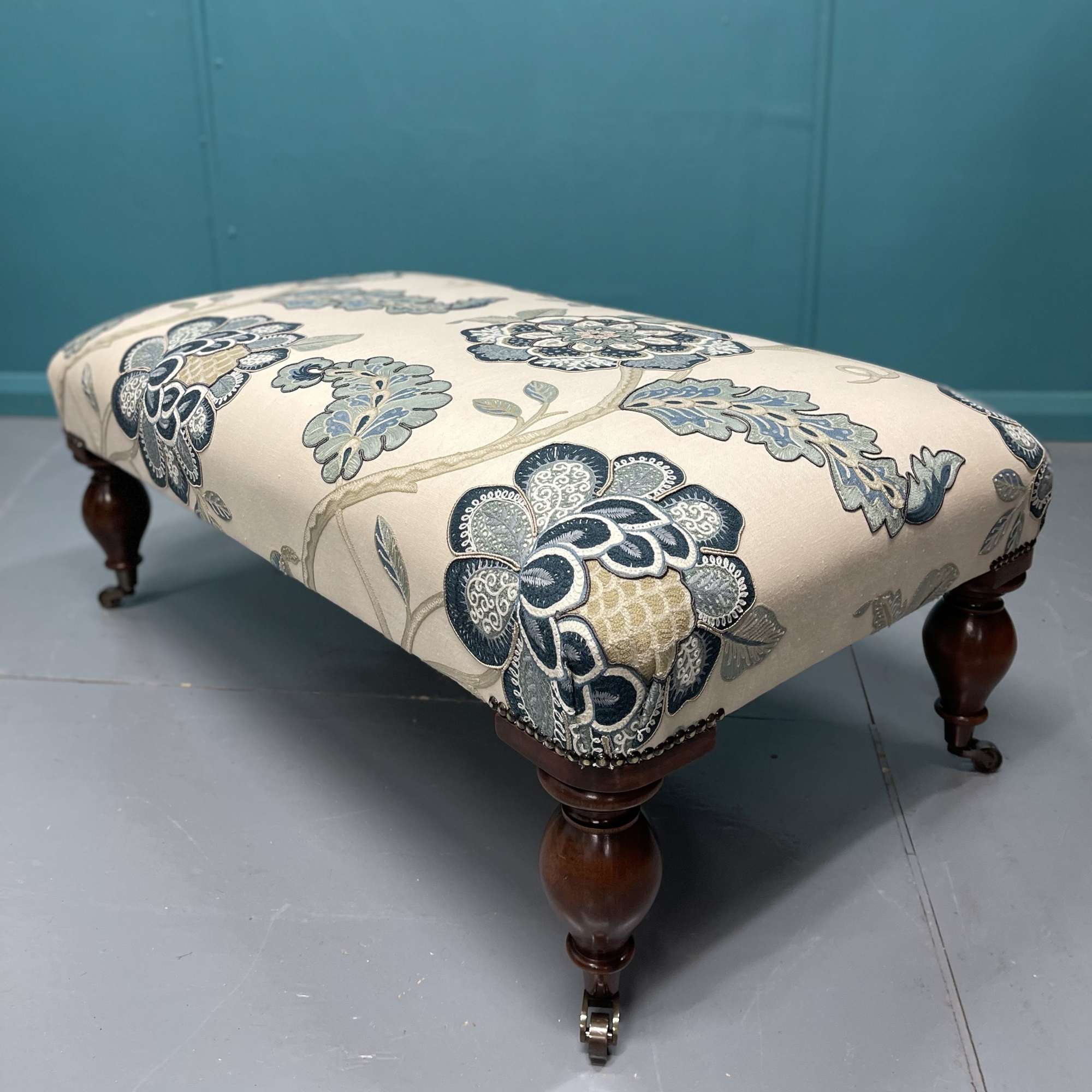 Newly upholstered ottoman footstool on castors