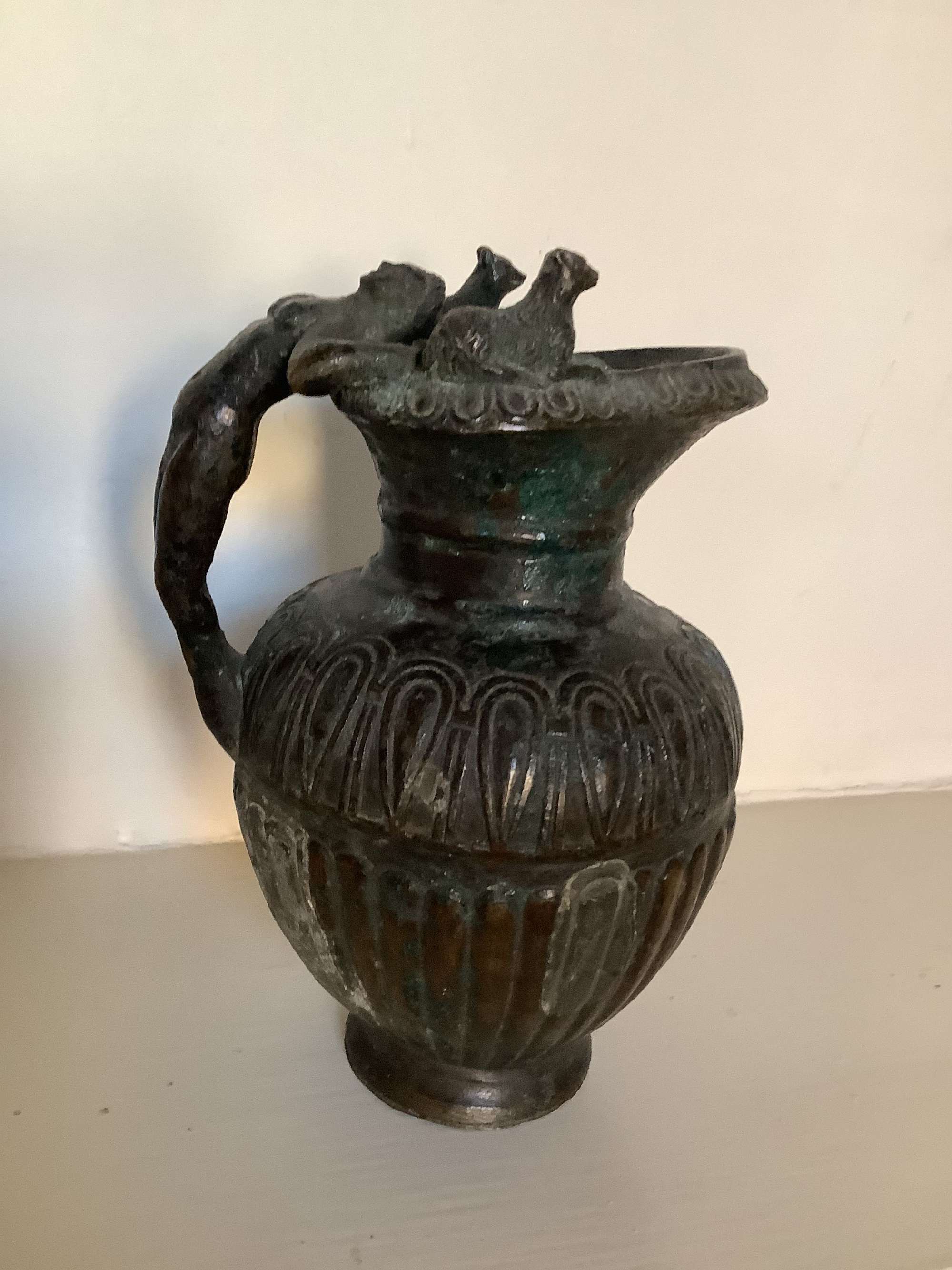 A heavily patinated bronze jug the handle depicting Dionysus the God of wine and pleasure