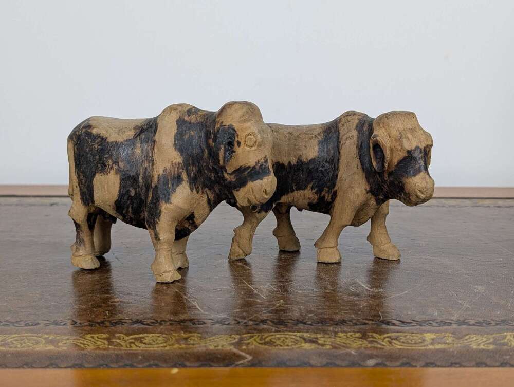 Pair of folk art carved wooden bulls with black painted markings, likely Indian, antique