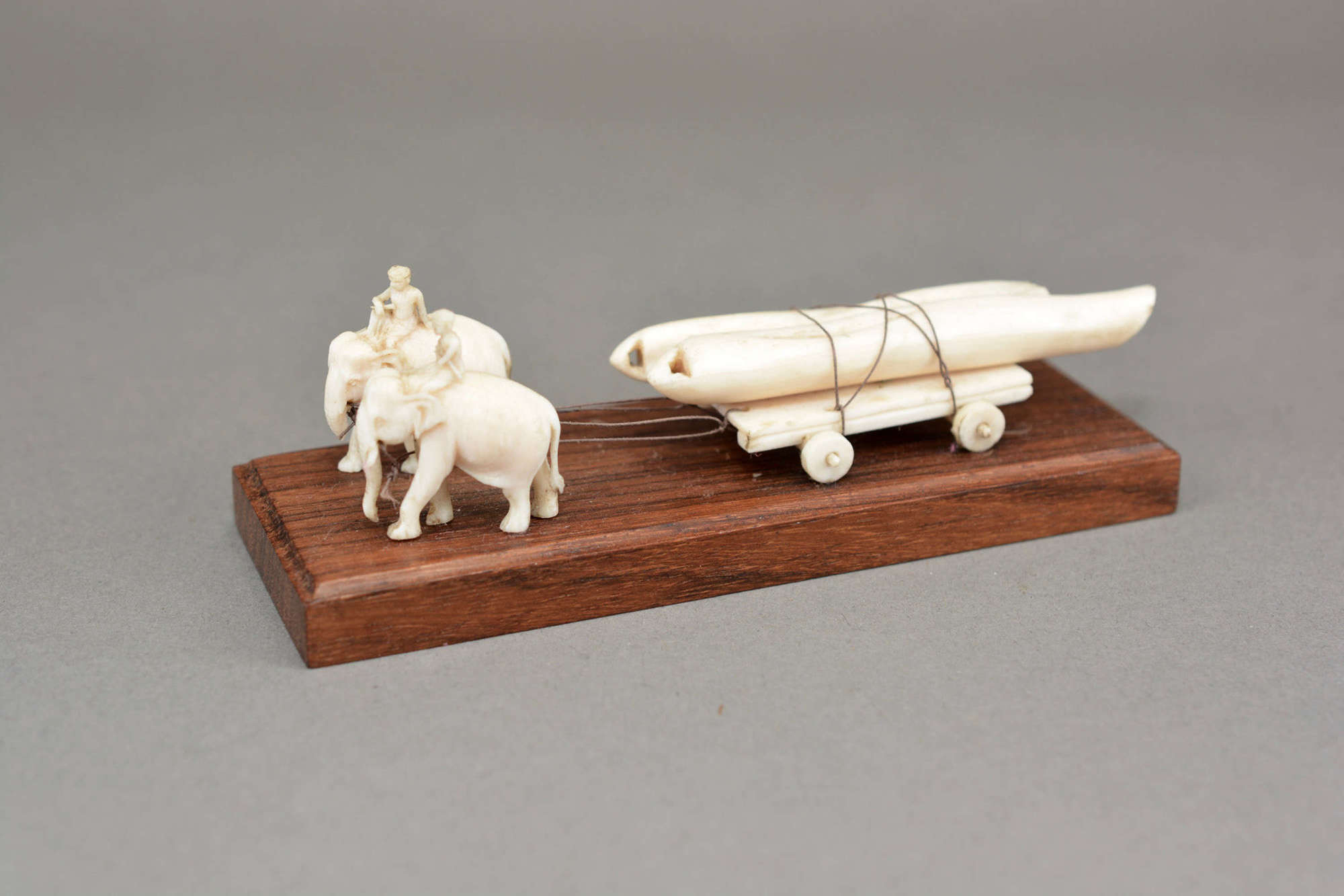 Hand carved model elephants pulling a log cart