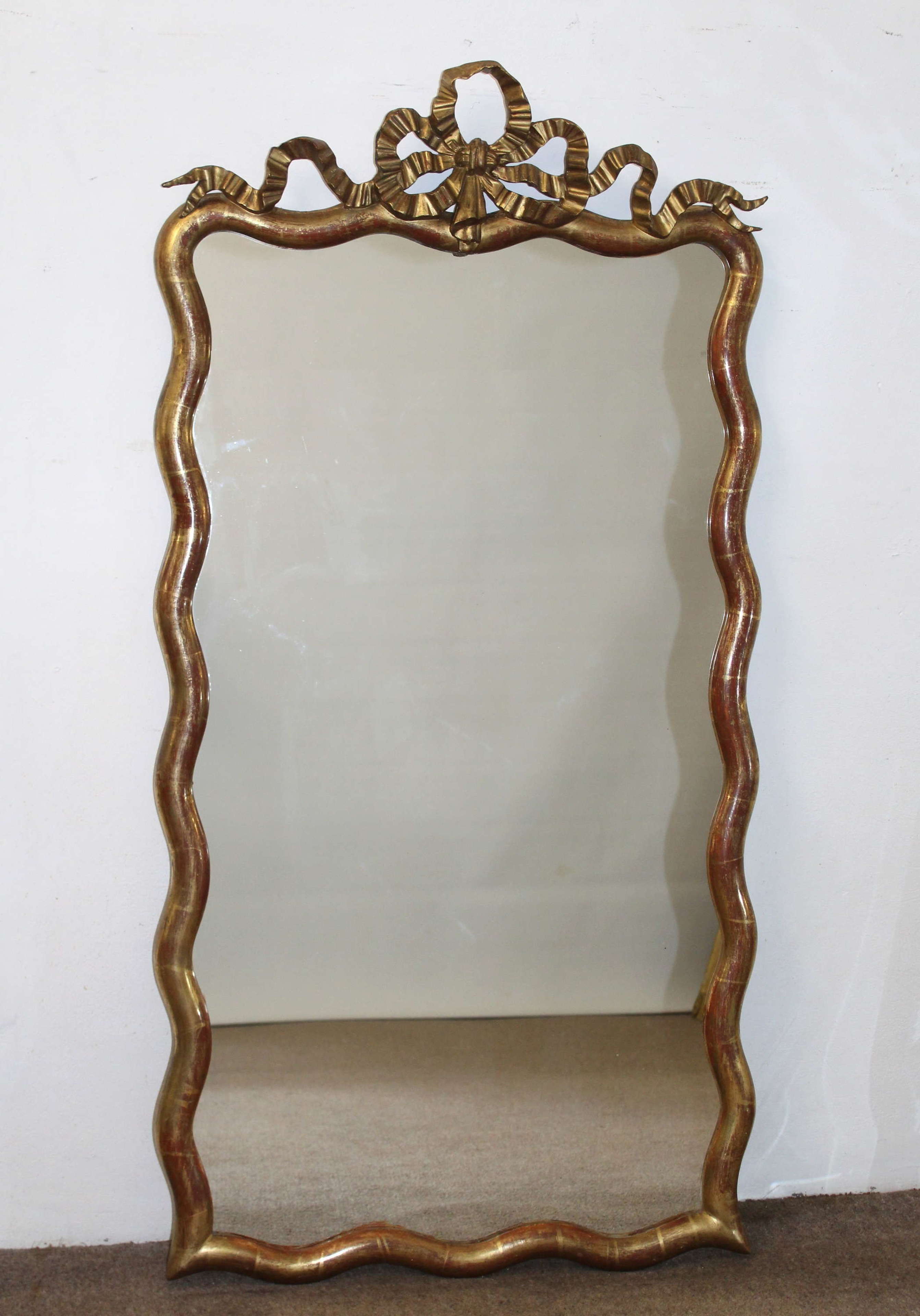 Antique French mirror with wavy frame and bow cartouche